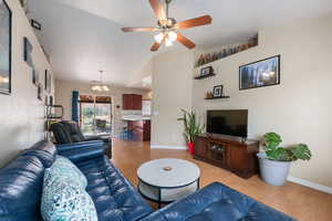 Living area featuring light wood-style flooring, a chandelier, and a ceiling fan