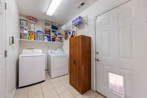 Laundry area featuring washing machine and clothes dryer and light tile patterned flooring