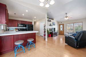 Kitchen featuring a kitchen bar, black appliances, a peninsula, light wood-type flooring, and ceiling fan