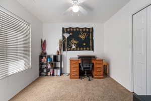 Carpeted office space featuring a ceiling fan and baseboards