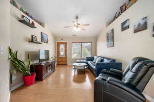Living room featuring light wood-type flooring, a ceiling fan, and lofted ceiling