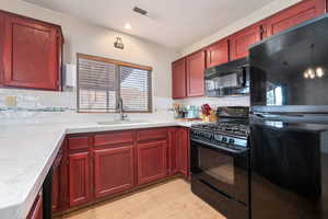 Kitchen featuring black appliances, reddish brown cabinets, light wood finished floors, and recessed lighting