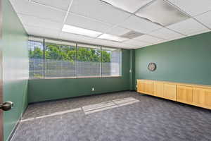 Empty room with dark colored carpet and a paneled ceiling