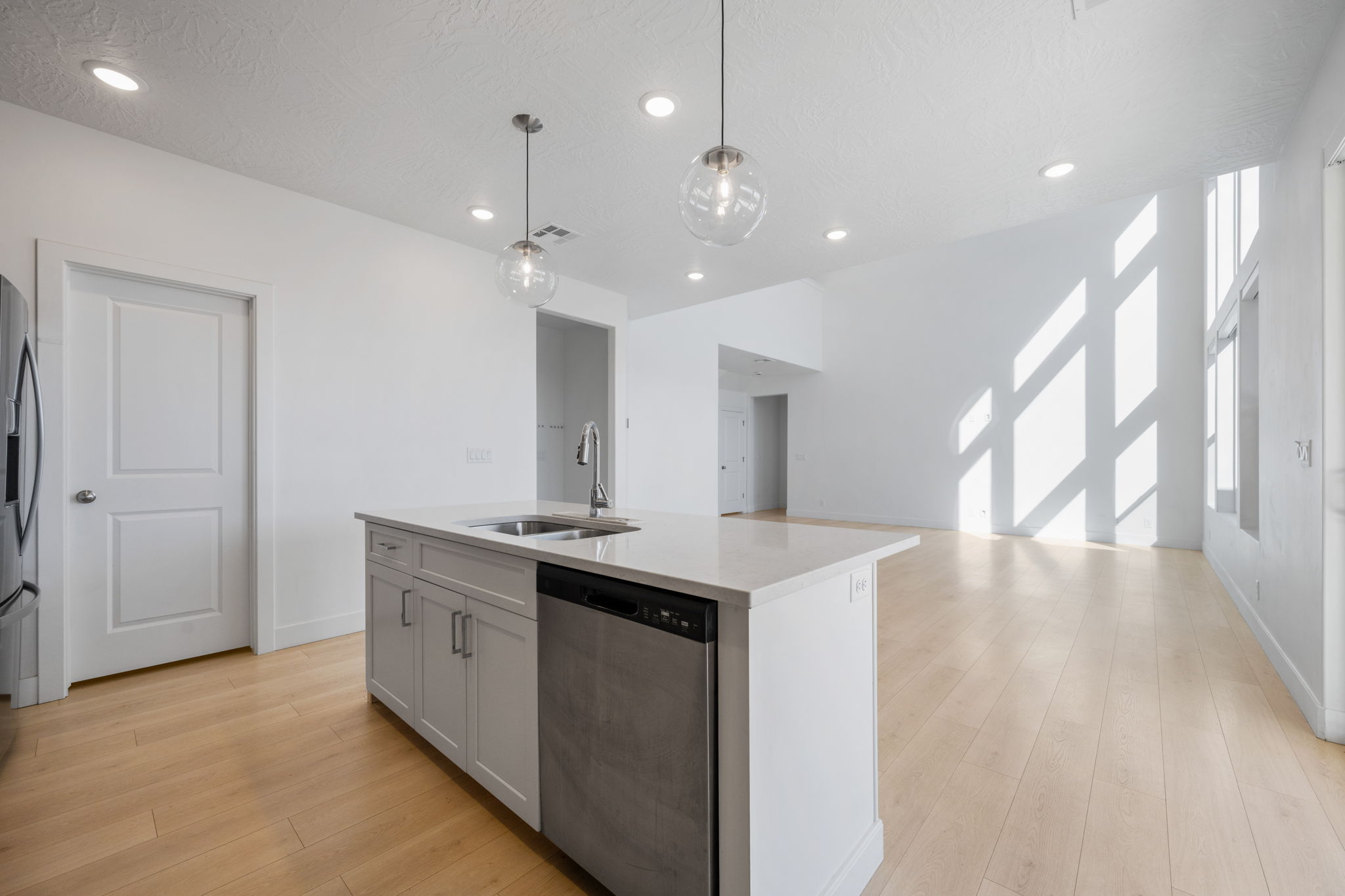 Kitchen featuring stainless steel appliances, a kitchen island with sink, pendant lighting, light wood-style floors, and recessed lighting