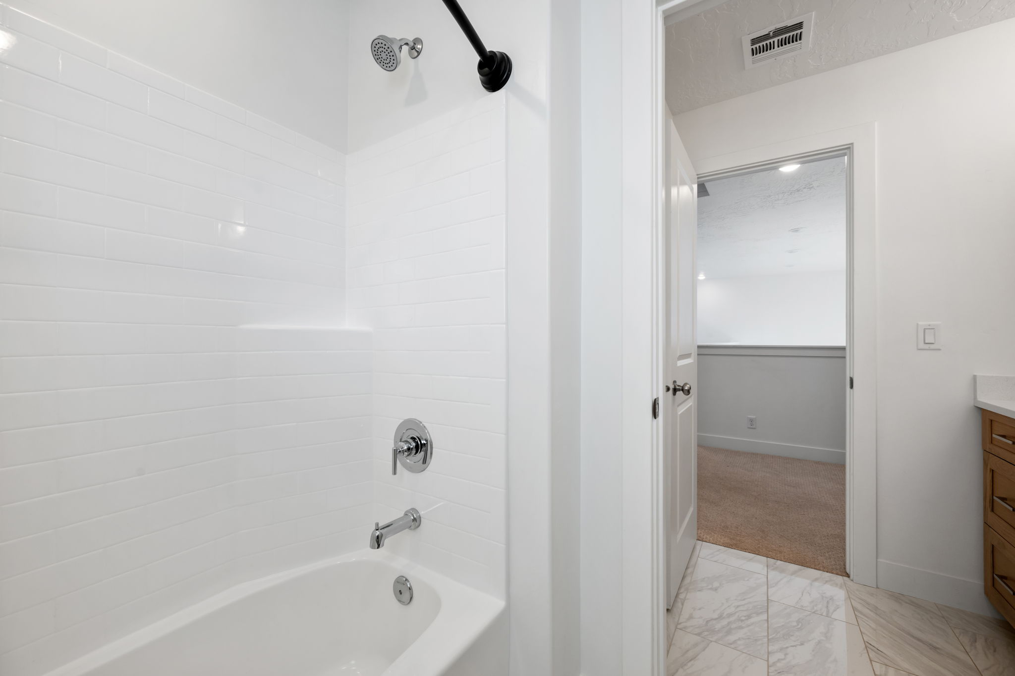 Bathroom featuring vanity, bathing tub / shower combination, light marble finish floors, and light carpet