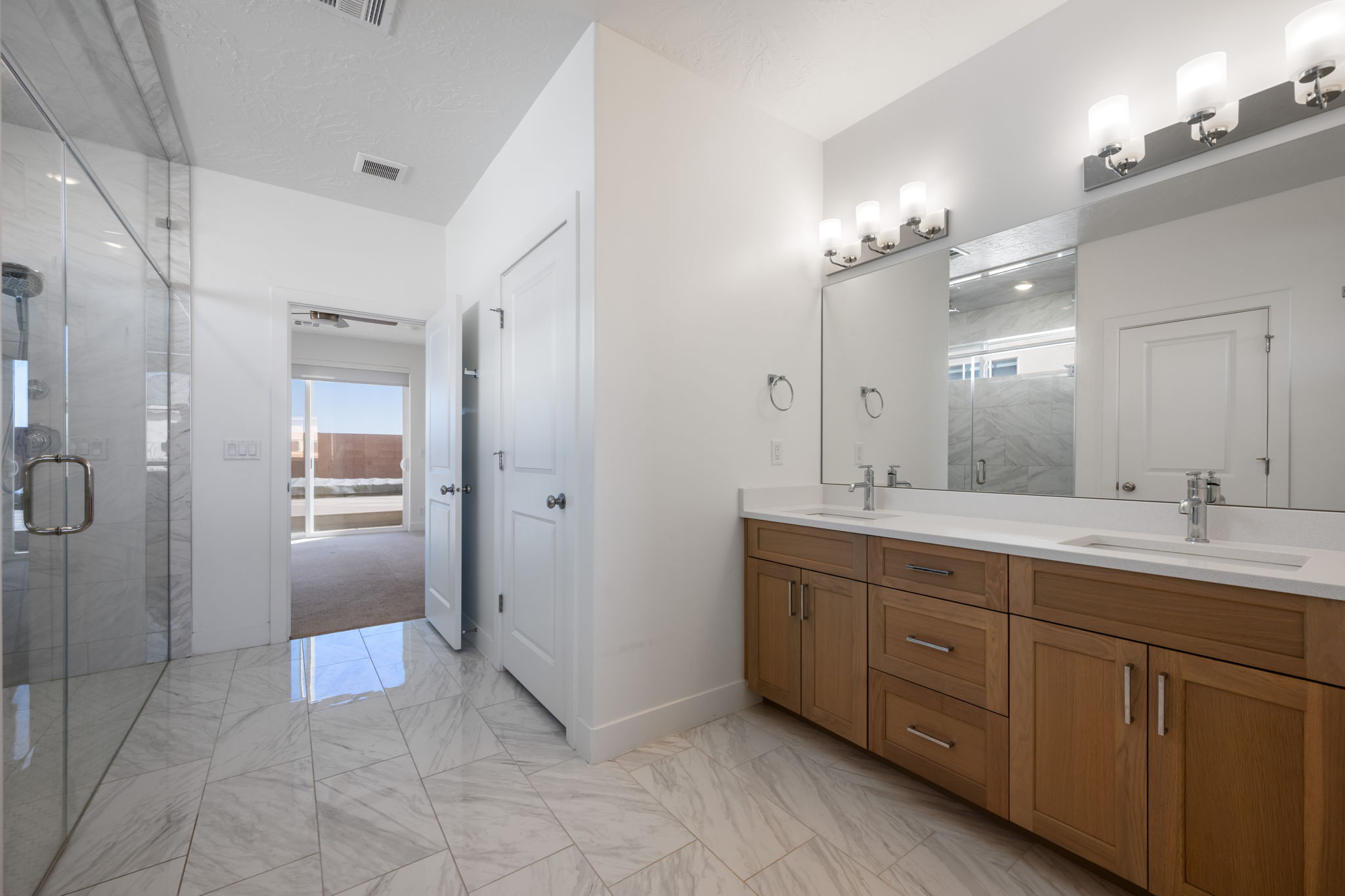 Full bath featuring a marble finish shower, light marble finish flooring, and double vanity