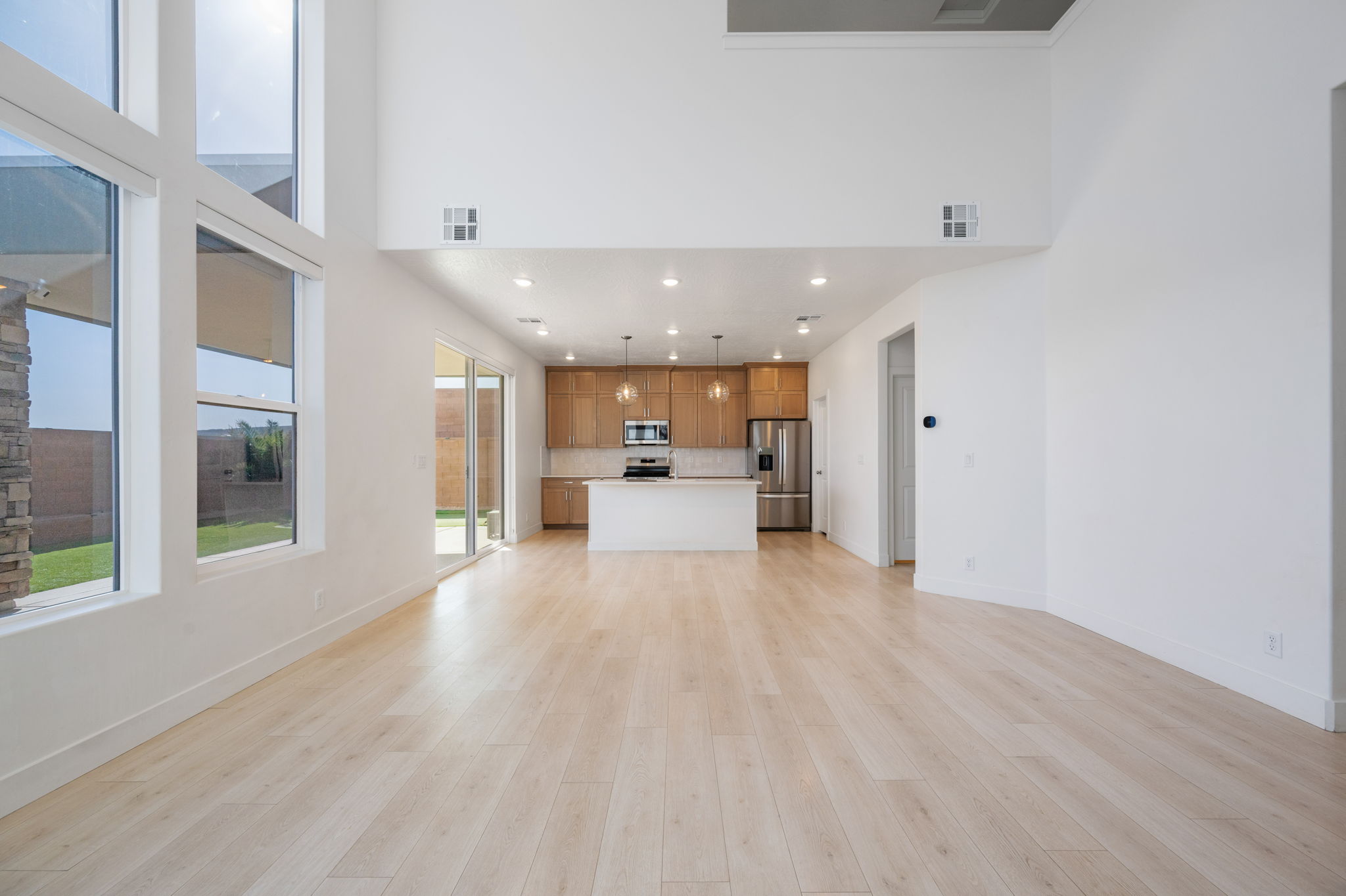 Unfurnished living room featuring recessed lighting, light wood finished floors, and a towering ceiling