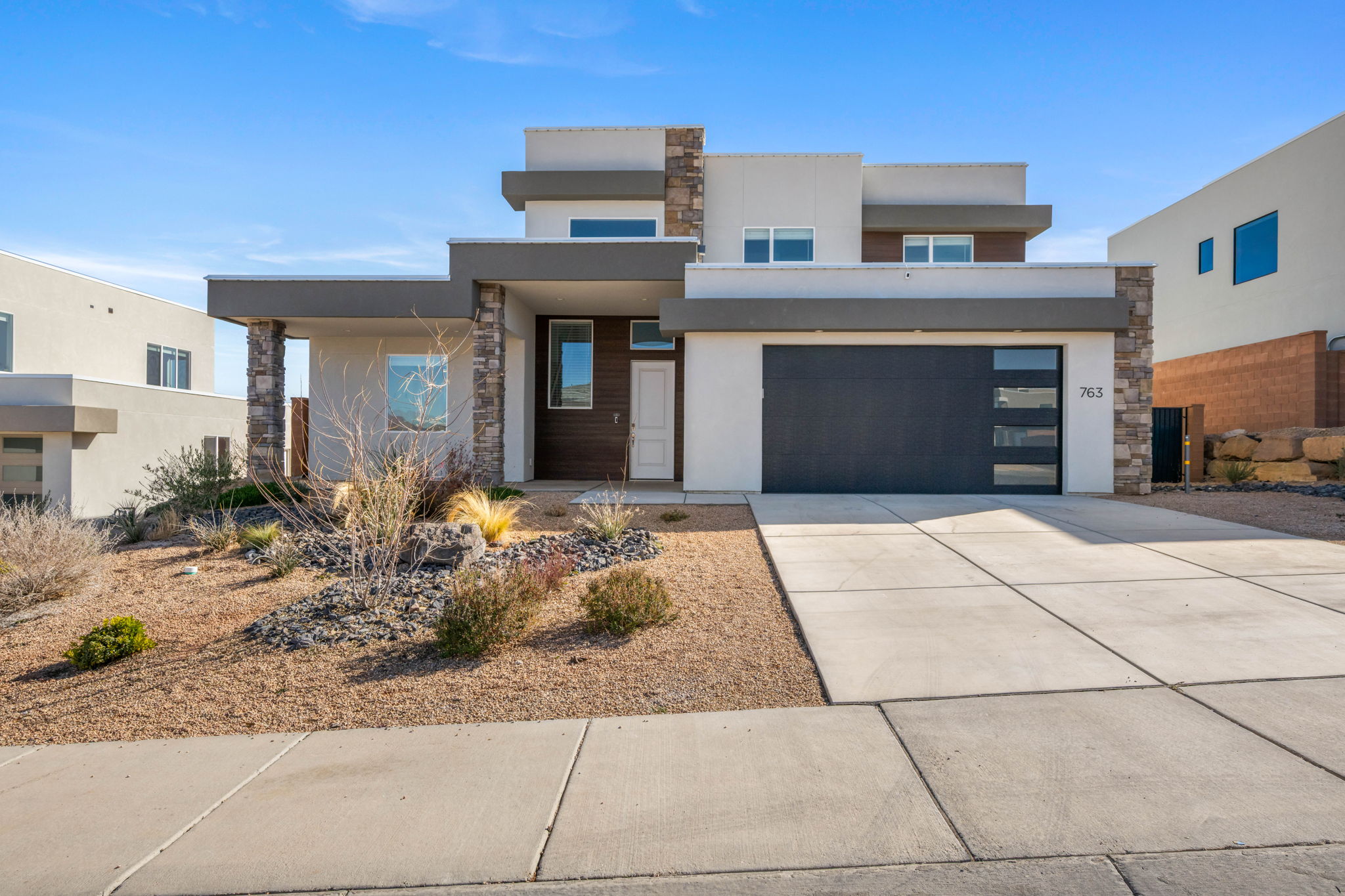 Contemporary home with stone siding, stucco siding, driveway, and a garage