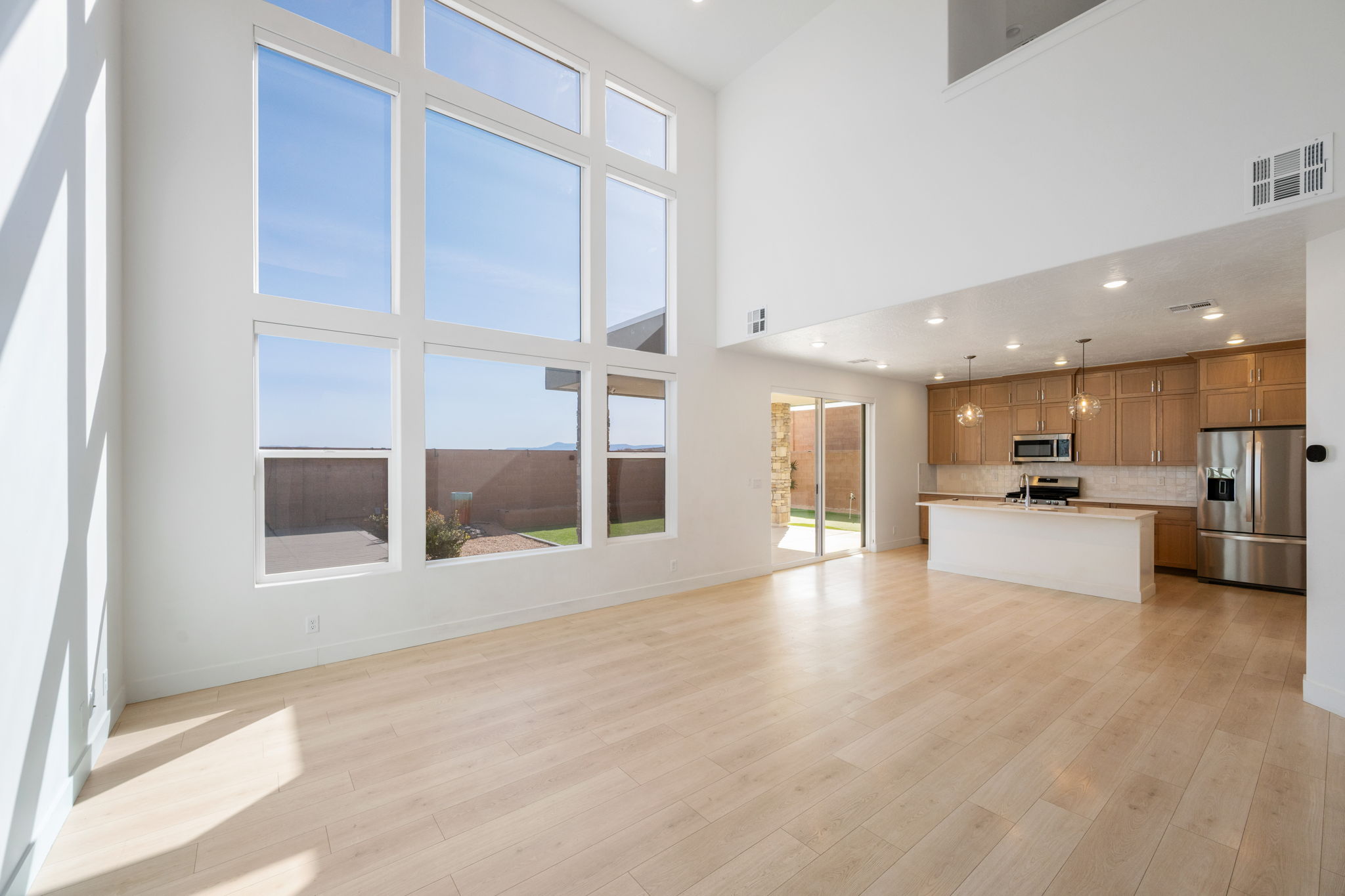 Unfurnished living room with recessed lighting, light wood-type flooring, and a towering ceiling