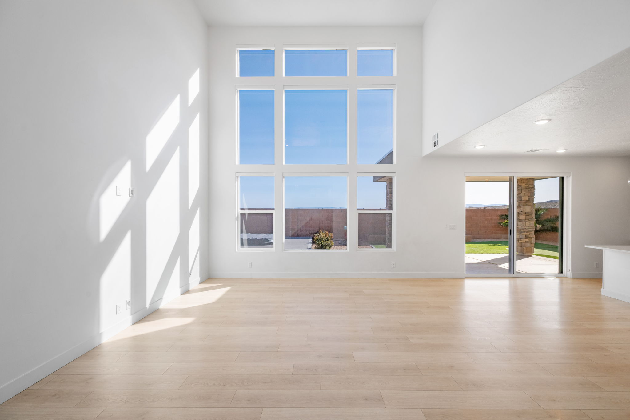 Unfurnished room featuring light wood-style flooring, a towering ceiling, and recessed lighting