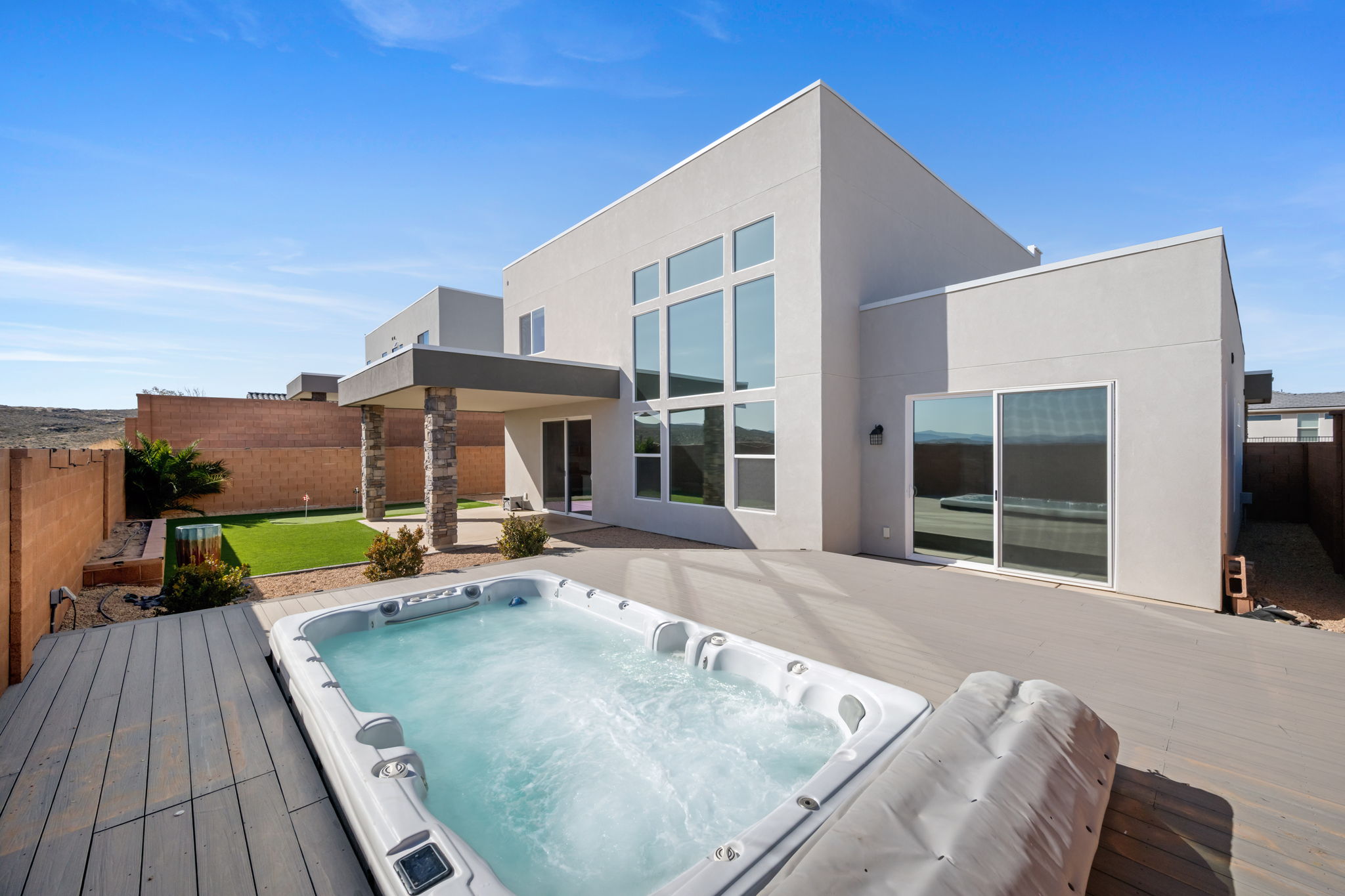 Back of property featuring a fenced backyard, stucco siding, a patio, and a wooden deck