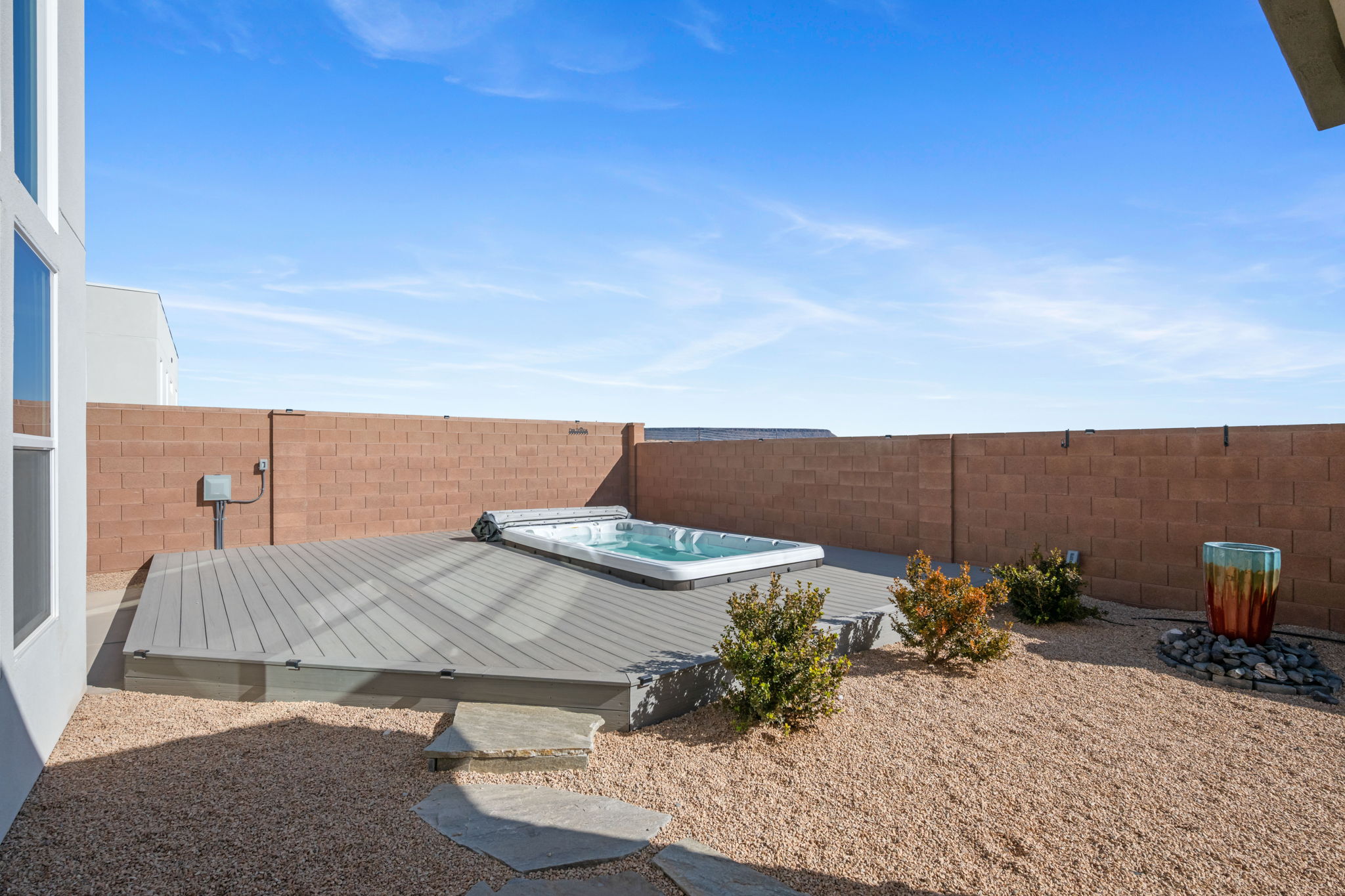 Fenced backyard with a hot tub and a wooden deck