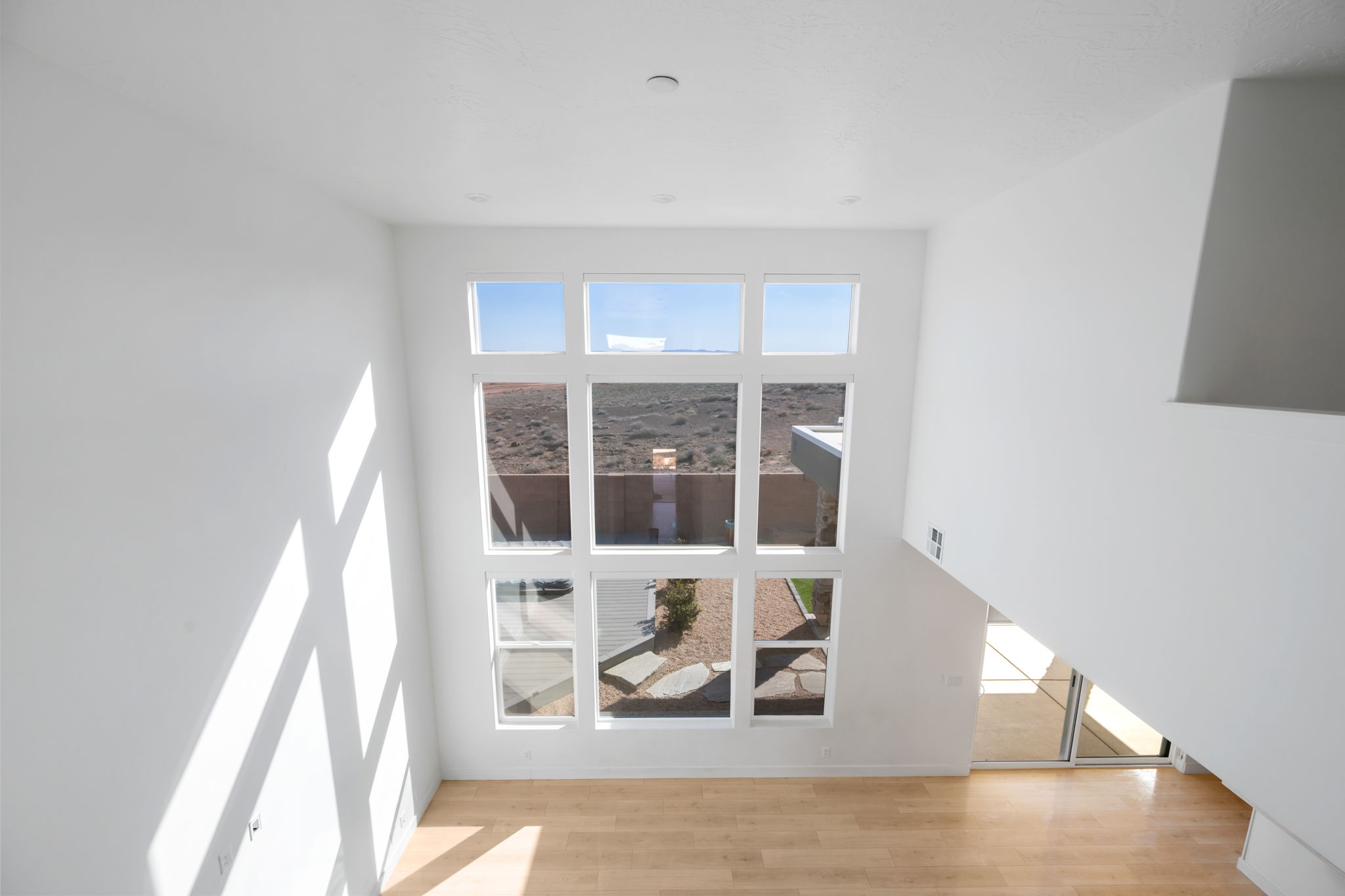 Unfurnished living room with light wood-style flooring and a towering ceiling