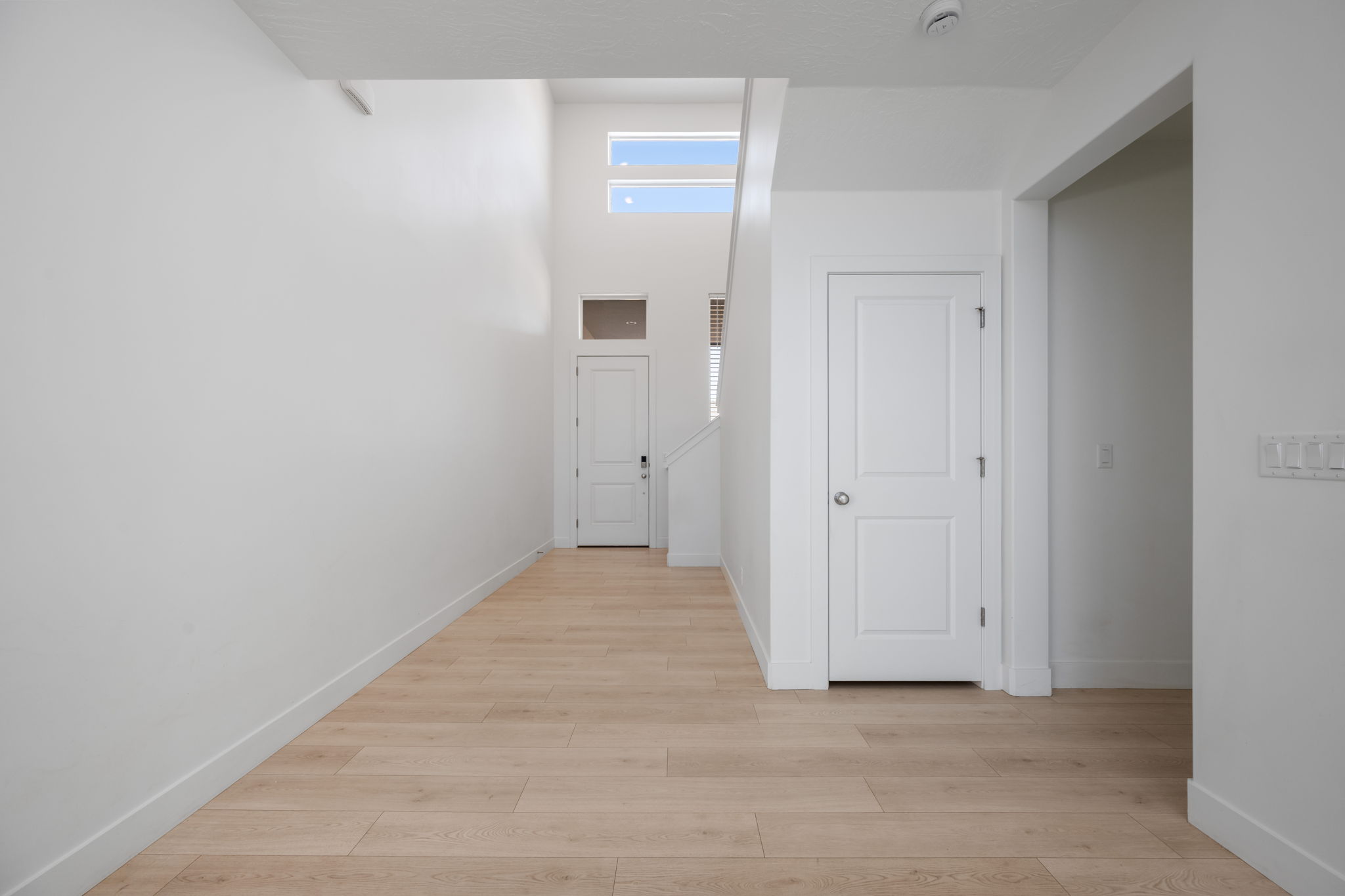 Corridor with light wood finished floors and a high ceiling