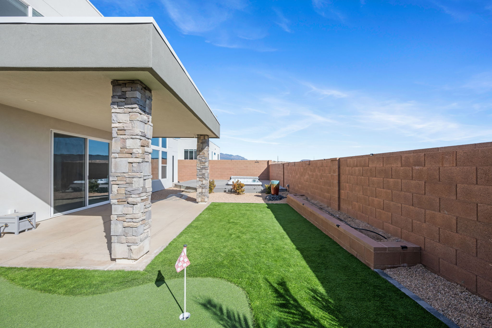 Fenced backyard with a patio area and a putting area