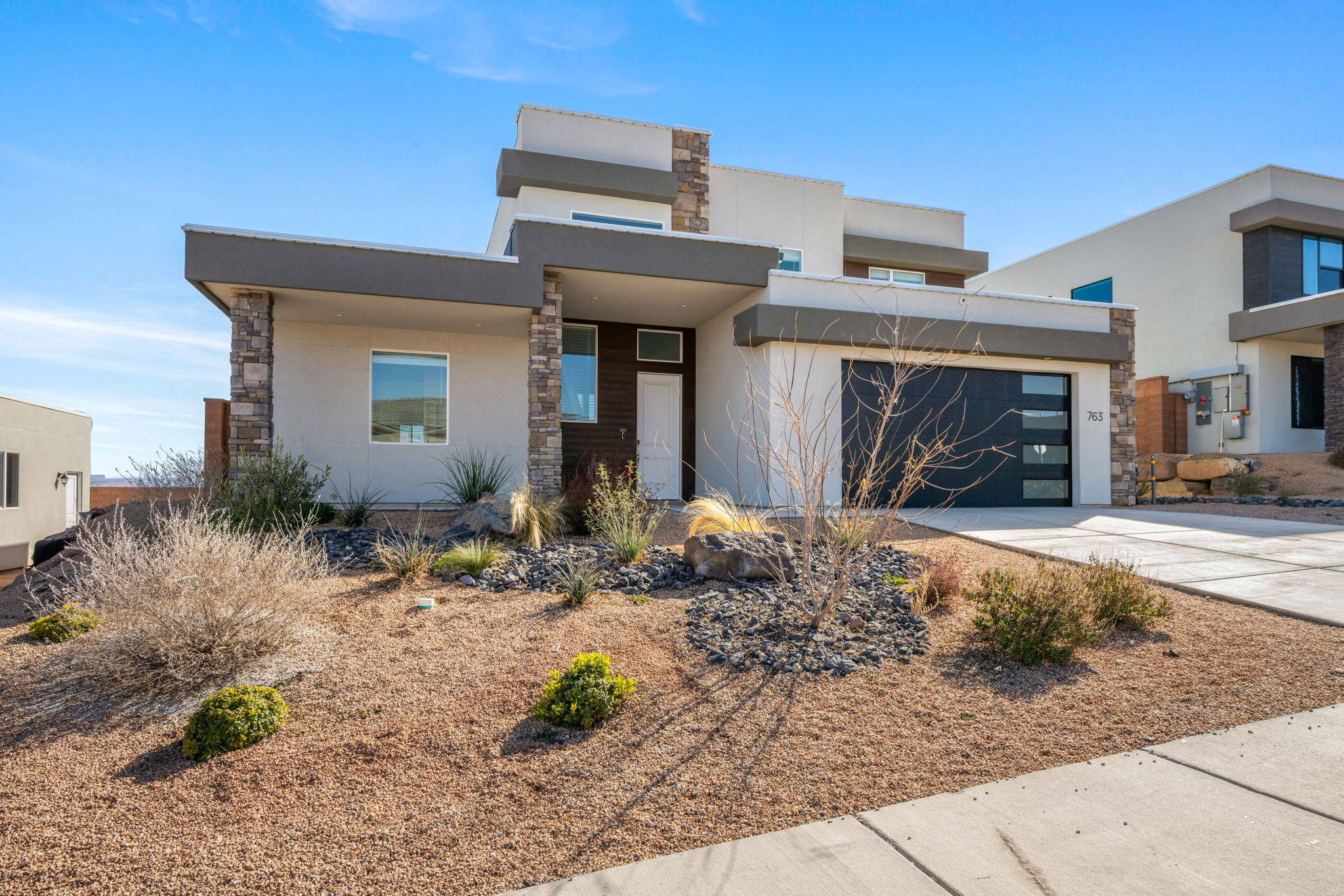 Modern home featuring stone siding, stucco siding, driveway, and an attached garage