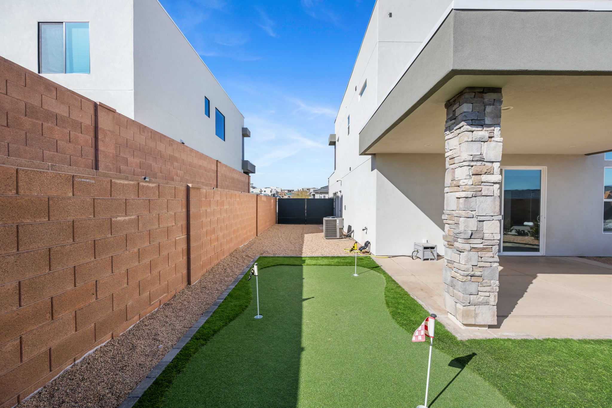 Fenced backyard featuring an area to practice putting and a patio area