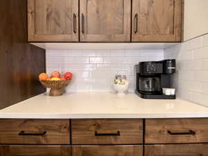 Kitchen featuring wood finish cabinetry, backsplash, and light stone counters
