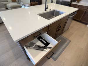 Kitchen with dark wood finish cabinets, light wood-style floors, a kitchen island with sink, and stainless steel appliances
