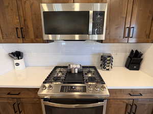 Kitchen with stainless steel appliances, wood finish cabinets, and backsplash
