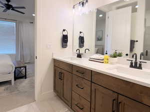 Full bathroom with ensuite bathroom, double vanity, light carpet, and a ceiling fan