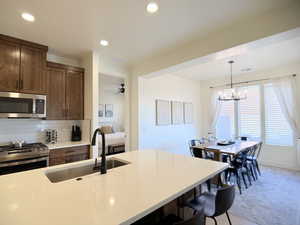 Kitchen with stainless steel appliances, light stone countertops, decorative backsplash, a ceiling fan, and a breakfast bar