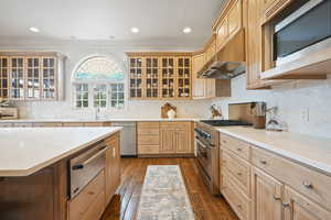 Kitchen featuring a warming drawer, appliances with stainless steel finishes, dark wood finished floors, under cabinet range hood, and crown molding