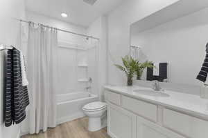 Bathroom featuring light wood-style floors, shower / bath combo with shower curtain, and vanity