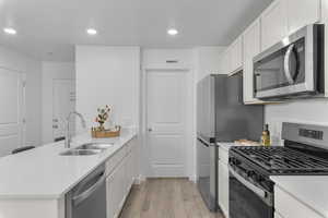 Kitchen with appliances with stainless steel finishes, a peninsula, white cabinetry, light stone counters, and recessed lighting
