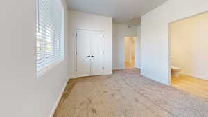 Unfurnished bedroom featuring light carpet and a closet