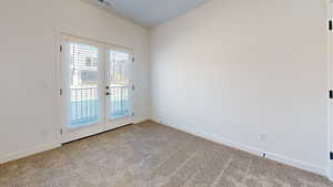 Carpeted spare room with french doors and baseboards