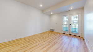 Empty room with french doors, light wood-type flooring, and recessed lighting
