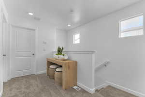 Corridor with an upstairs landing, light carpet, and recessed lighting