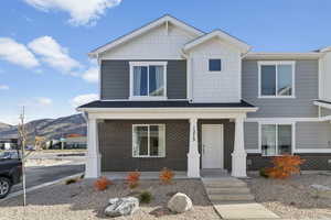 View of front of property featuring covered porch, brick siding, a mountain view, and roof with shingles