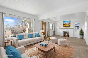 Living room featuring carpt flooring, a brick fireplace, and a textured ceiling