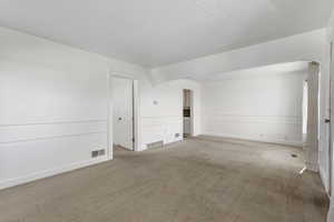 Carpeted spare room featuring baseboards