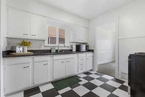 Kitchen featuring dark floors, white cabinets, dark stone counters, gas stove, and stainless steel microwave