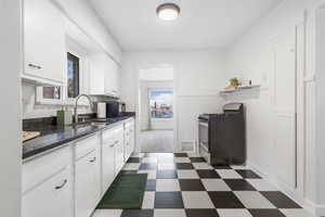 Kitchen featuring dark floors, stainless steel gas range, dark stone countertops, white cabinetry, and black microwave