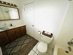 Full bathroom featuring vanity, bathtub / shower combination, and dark tile patterned floors