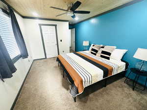 Carpeted bedroom featuring ceiling fan and wooden ceiling