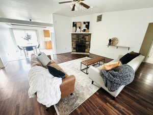 Living area featuring wood finished floors, a fireplace, lofted ceiling, and ceiling fan