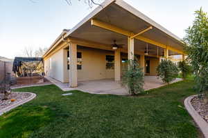 Back of house featuring a patio area, a ceiling fan, stucco siding, and a yard
