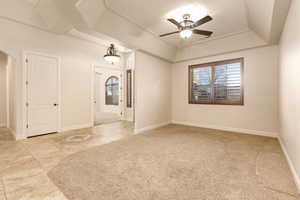 Spare room featuring ceiling fan, a raised ceiling, light carpet, and light tile patterned flooring