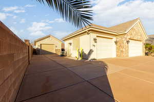 View of home's exterior featuring an outbuilding, stone siding, a garage, stucco siding, and driveway