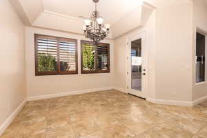 Spare room featuring plenty of natural light, a raised ceiling, and a chandelier
