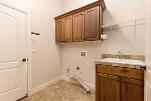 Washroom featuring cabinet space, hookup for an electric dryer, hookup for a washing machine, and hookup for a gas dryer