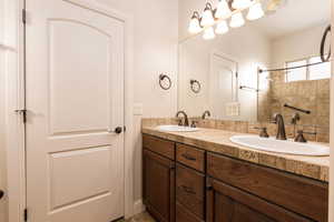 Full bath featuring double vanity and tiled shower