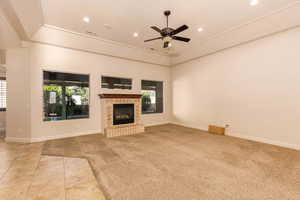 Unfurnished living room featuring light carpet, a fireplace, a ceiling fan, a raised ceiling, and recessed lighting