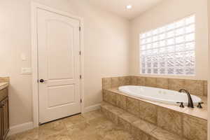 Bathroom with a garden tub, vanity, and recessed lighting
