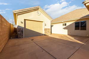 View of front of house with stone siding, an outdoor structure, driveway, a garage, and stucco siding